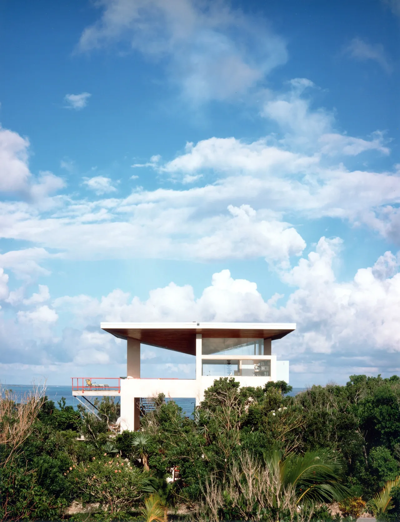 The Taylor Vacation Home features a flat overhanging wooden roof and glass walls with an ocean view, designed by Frank Harmon Architect PA.