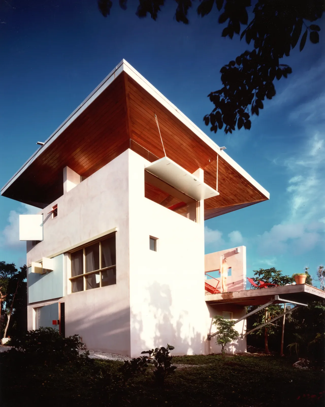 Taylor Vacation Home features a flat roof with a wide overhanging wood ceiling and white stucco walls.