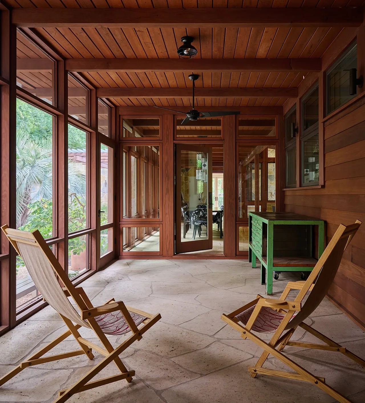 The Foothill Terrace covered patio features wood ceiling beams, large wood-framed windows, and natural stone flooring.