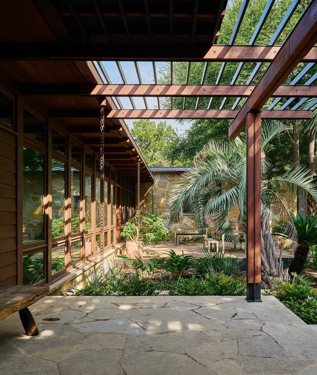 The FOOTHILL TERRACE patio features a wooden pergola, flagstone flooring, and lush landscaping with palms and shrubs.