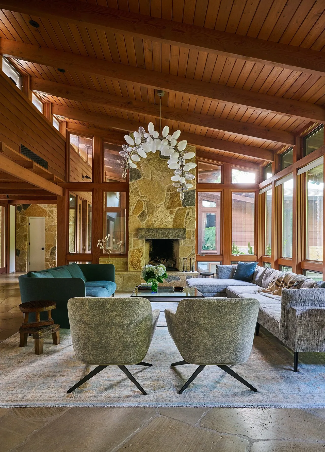 Living room features wood-paneled vaulted ceiling, stone fireplace, and ample windows for natural light.