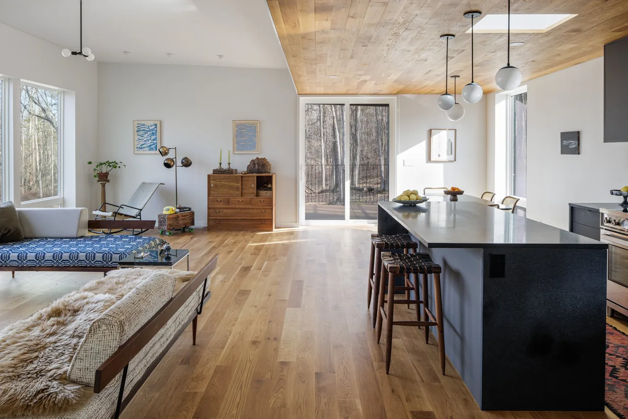 Open plan living and kitchen space featuring wood ceiling, hardwood floors, and large windows providing natural light.