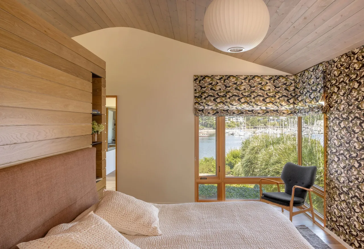 Bedroom with wood-paneled ceiling and a large window view of the marina at Eagle Harbor Residence.