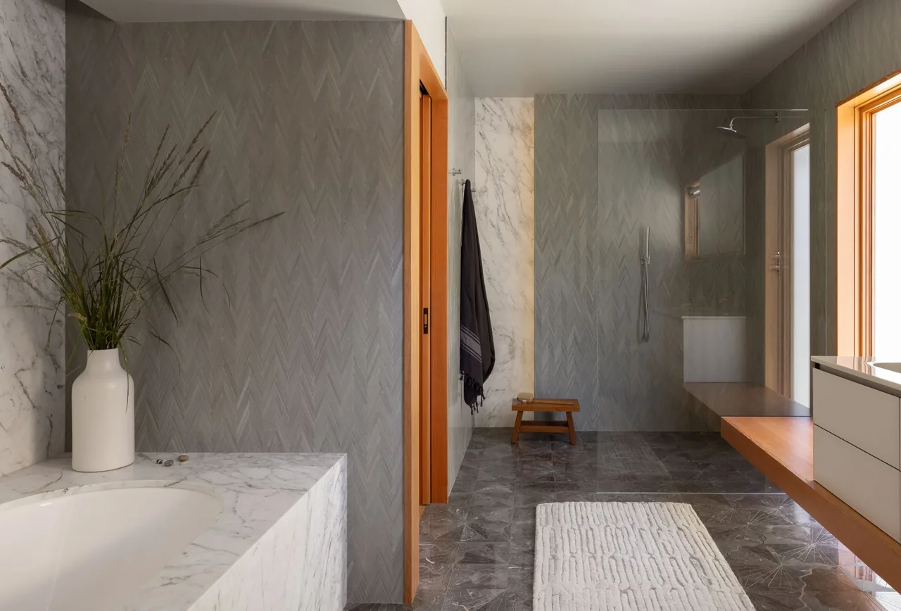 Bathroom in Eagle Harbor Residence featuring marble surfaces, a glass-enclosed shower, and wood accents.