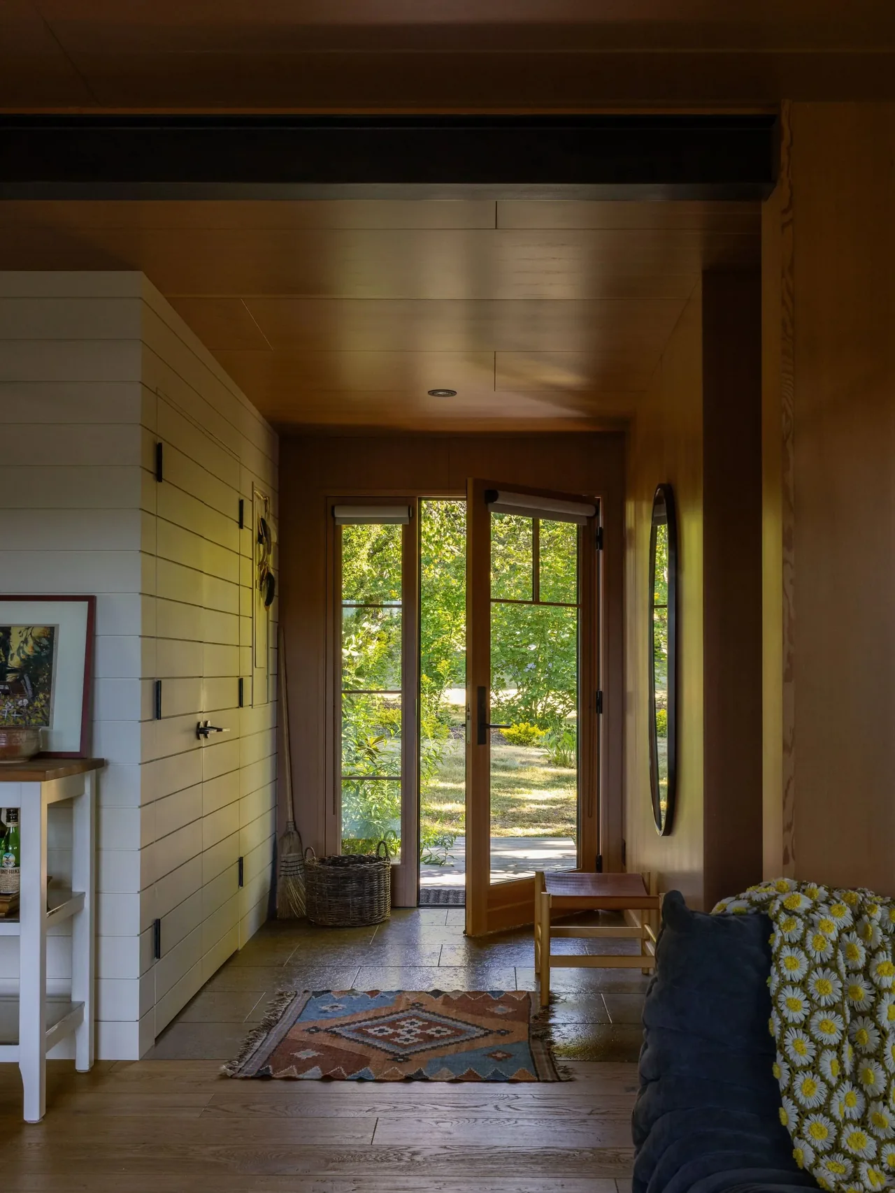 Eagle Harbor Residence entry hallway with wooden door and garden view, highlighting natural wood interiors by Graham Baba Architects