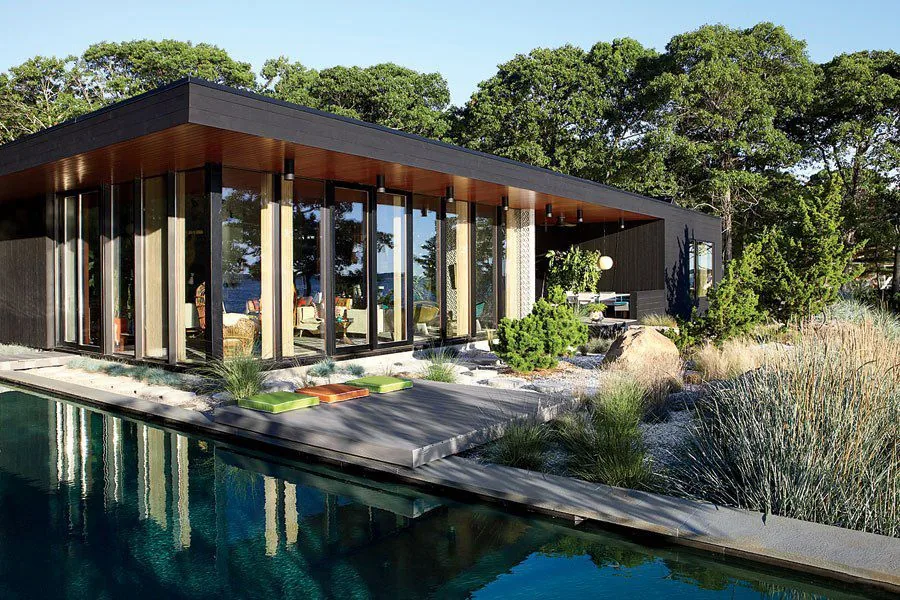 Seaside House features floor-to-ceiling glazing with black frames and a flat roof next to a rectangular pool.