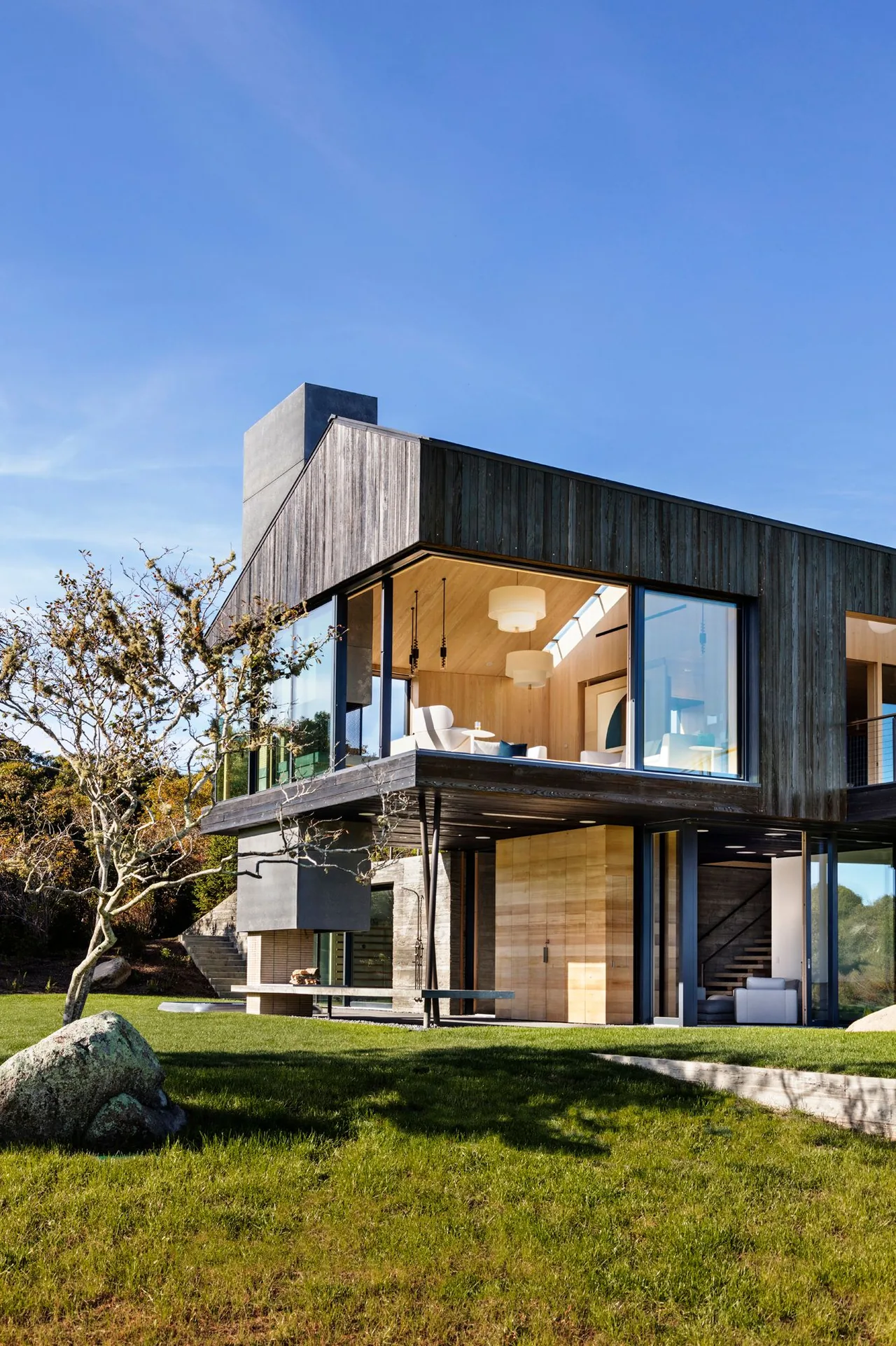 Seaside House features black wood siding with extensive floor-to-ceiling glazing to maximize natural light.