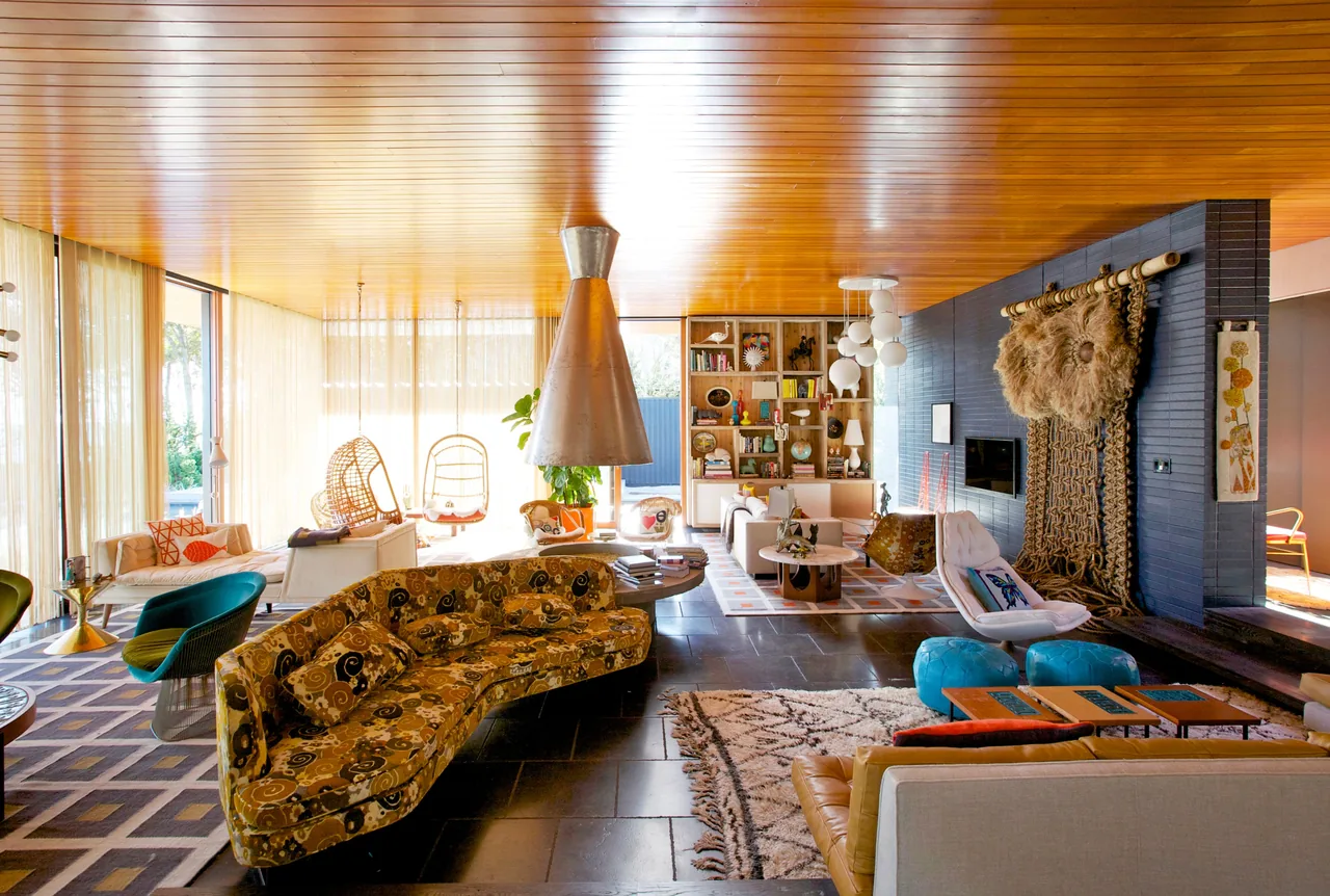 Living room of Seaside House with a wood ceiling soffit and distinctive midcentury modern furnishings.