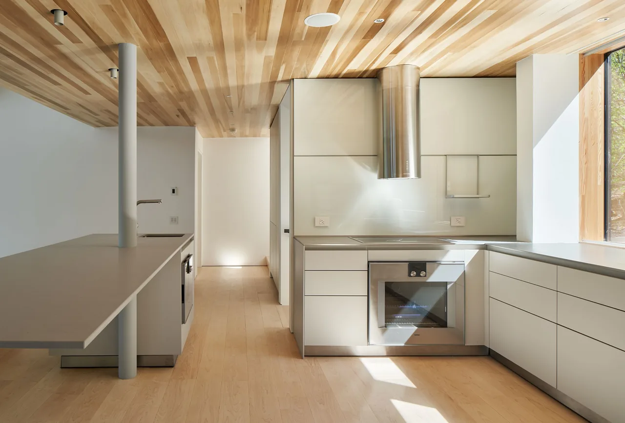 Schroon Lake House kitchen features clean lines, wood ceiling, and built-in appliances with a wood frame window providing natural light.