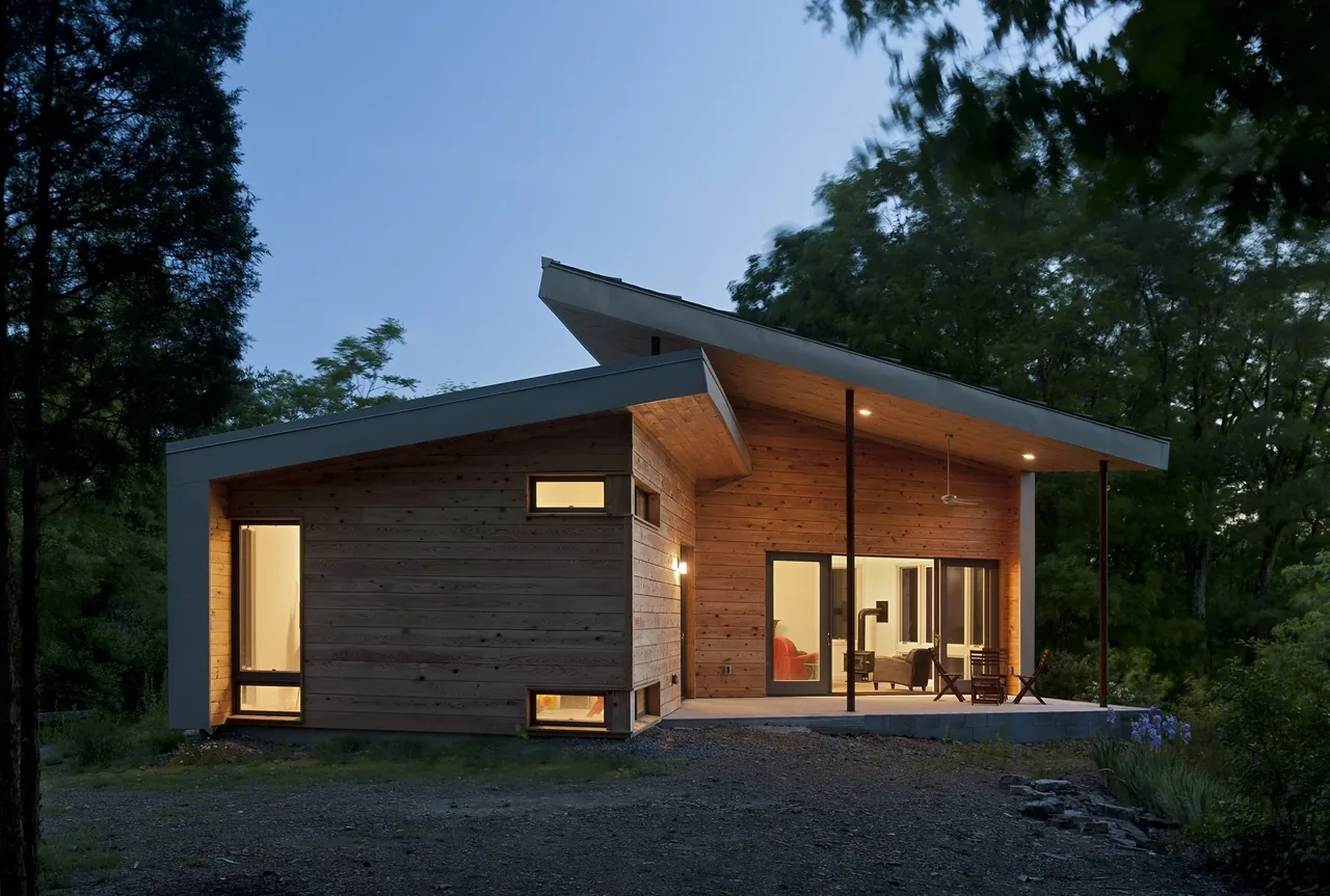 The Ridge House by GriD Architects features wood siding and a shed roof with a covered patio area.