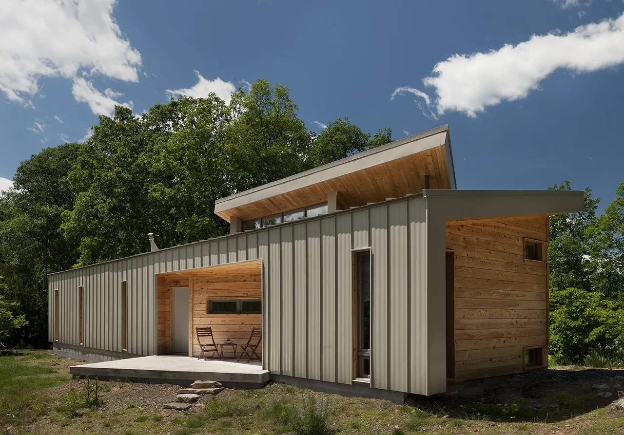 The Ridge House by GriD Architects features metal siding, wood accents, and a shed roof in a wooded setting.