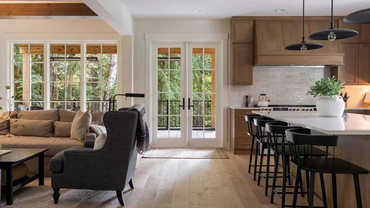 The Cougar Mt Custom features a bright kitchen and living area with glass panel double doors and light hardwood flooring.