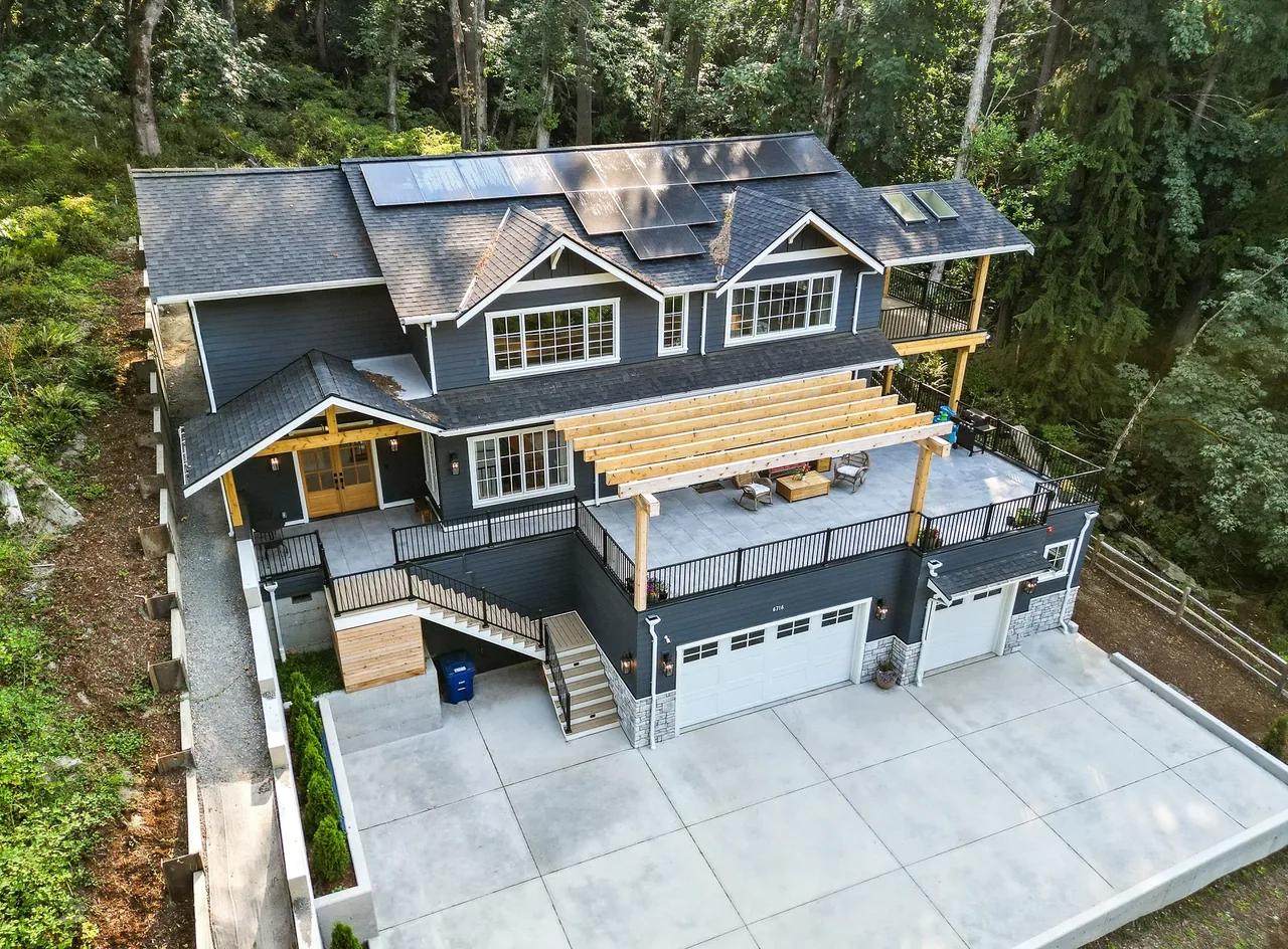 Cougar Mt Custom house features extensive outdoor living space with a pergola and solar panels on the roof.