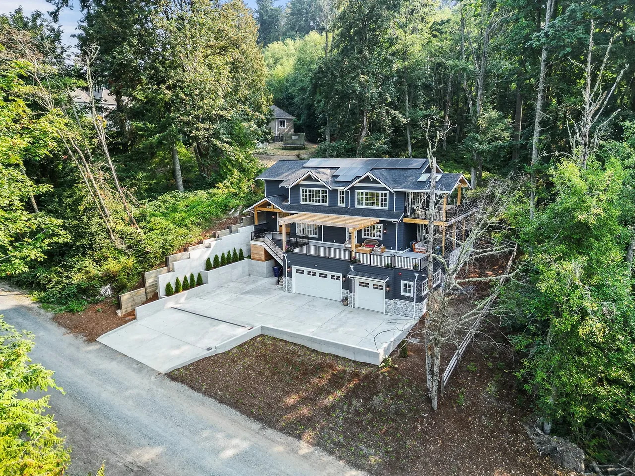 The Cougar Mt Custom home by H2D architecture + design features dark siding, multiple gable roof sections, and a broad concrete driveway.