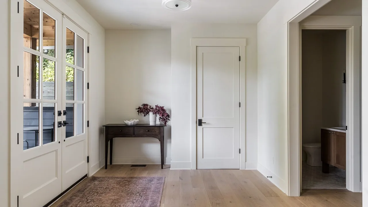 Entryway featuring glass double doors, a dark wood console table, and light hardwood flooring in Cougar Mt Custom project.