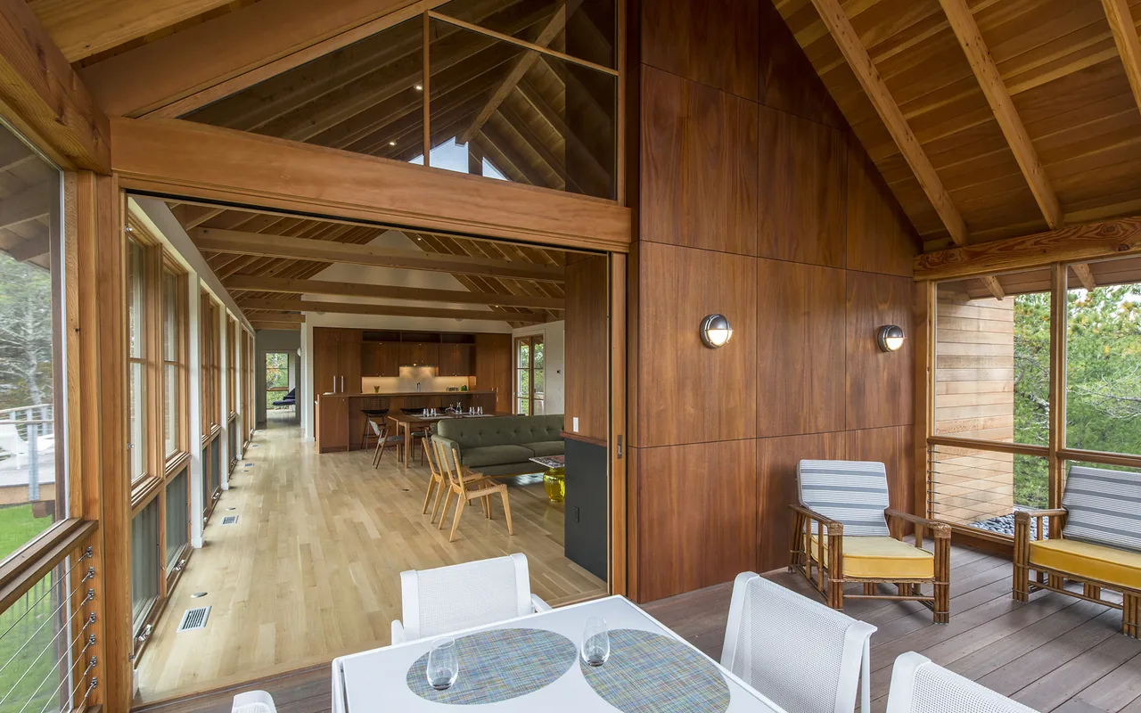 Screened porch connects to an open-plan kitchen and living area featuring wood paneling and vaulted ceilings.