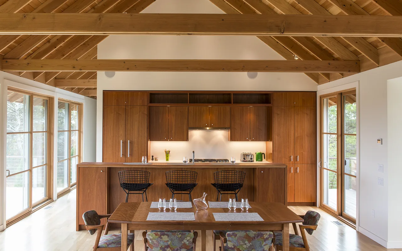 Kitchen and dining space featuring wood cabinetry, exposed beams, and large glass doors to outdoor areas.