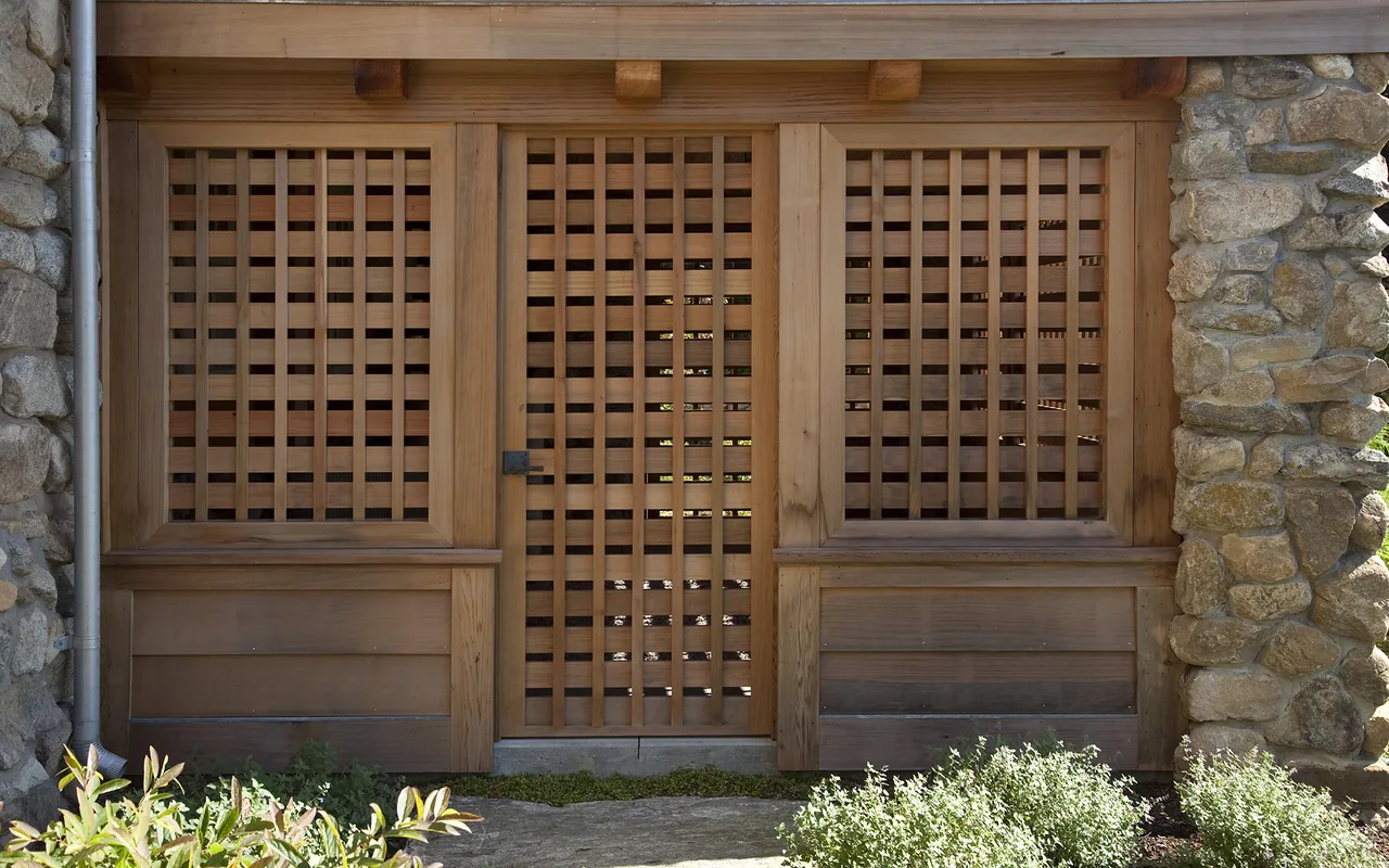 Wooden lattice entry gate flanked by matching lattice panels and stone columns.