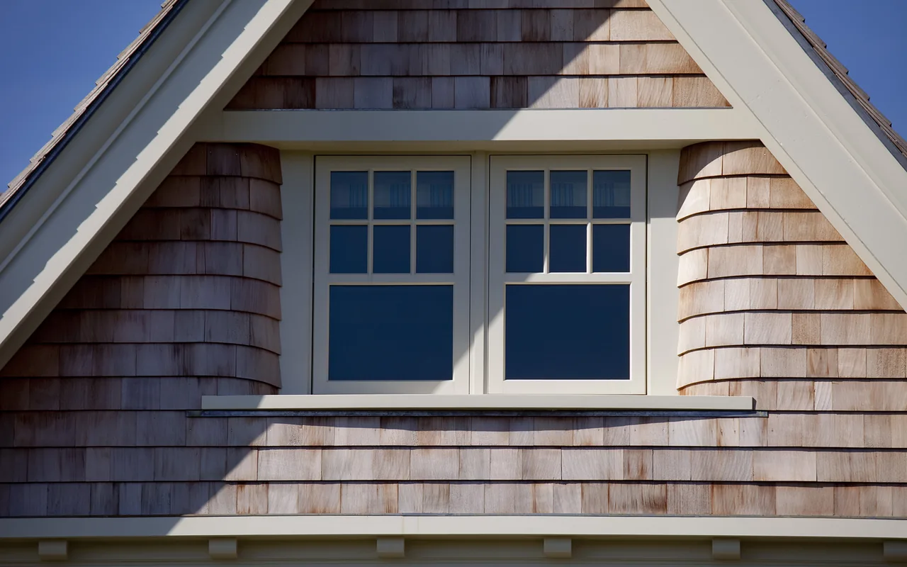The Watch Hill Rhode Island Residence features shingle siding and divided-lite double windows under a steep gable roof.