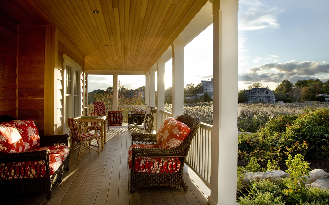 Covered porch with wicker seating and red patterned cushions offering a relaxed outdoor living space.