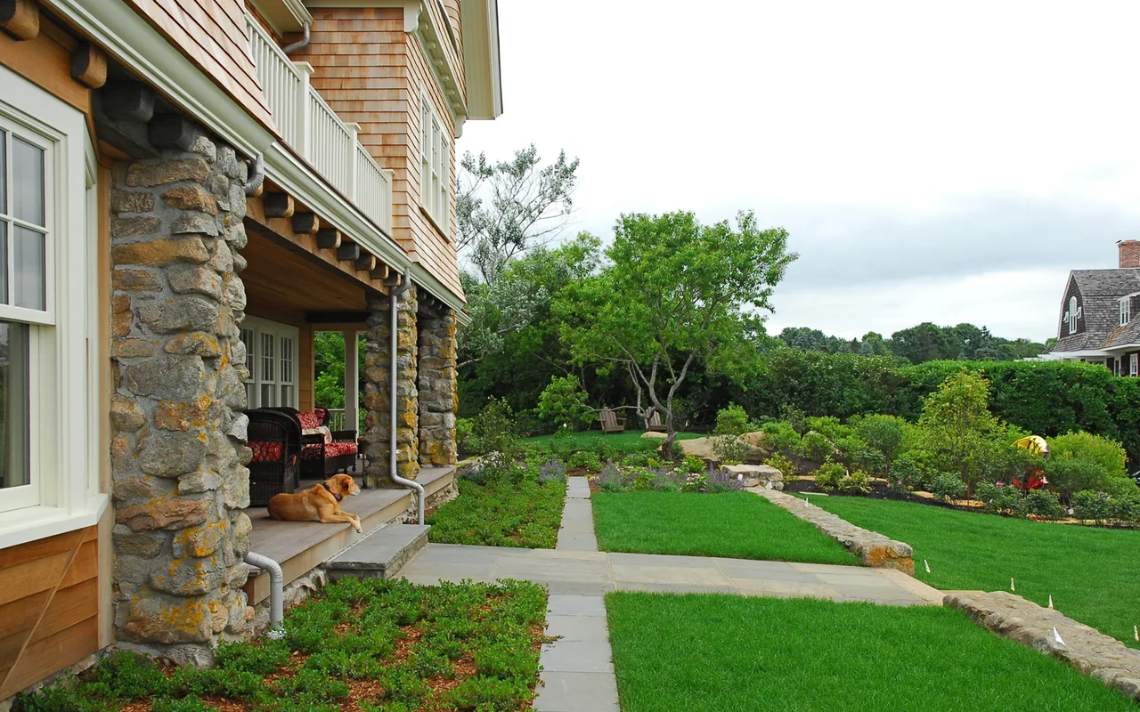 Watch Hill Rhode Island residence with stone porch columns and landscaped backyard seating area.