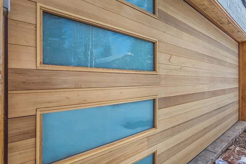 Exterior detail of horizontal wood plank siding with small rectangular windows on the Snowmass Village Weekender project.