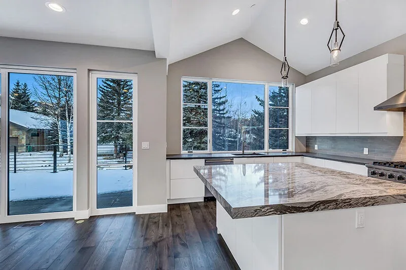 Kitchen of Snowmass Village Weekender featuring large windows with snowy mountain views and dark wood floors.