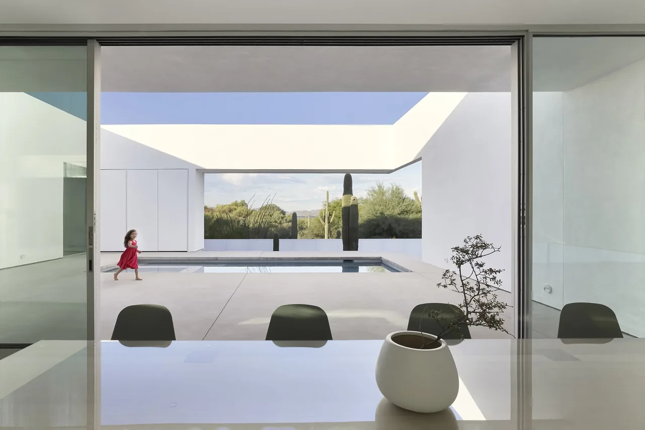 Modern house with sliding glass doors opening to a courtyard pool area with desert landscaping.