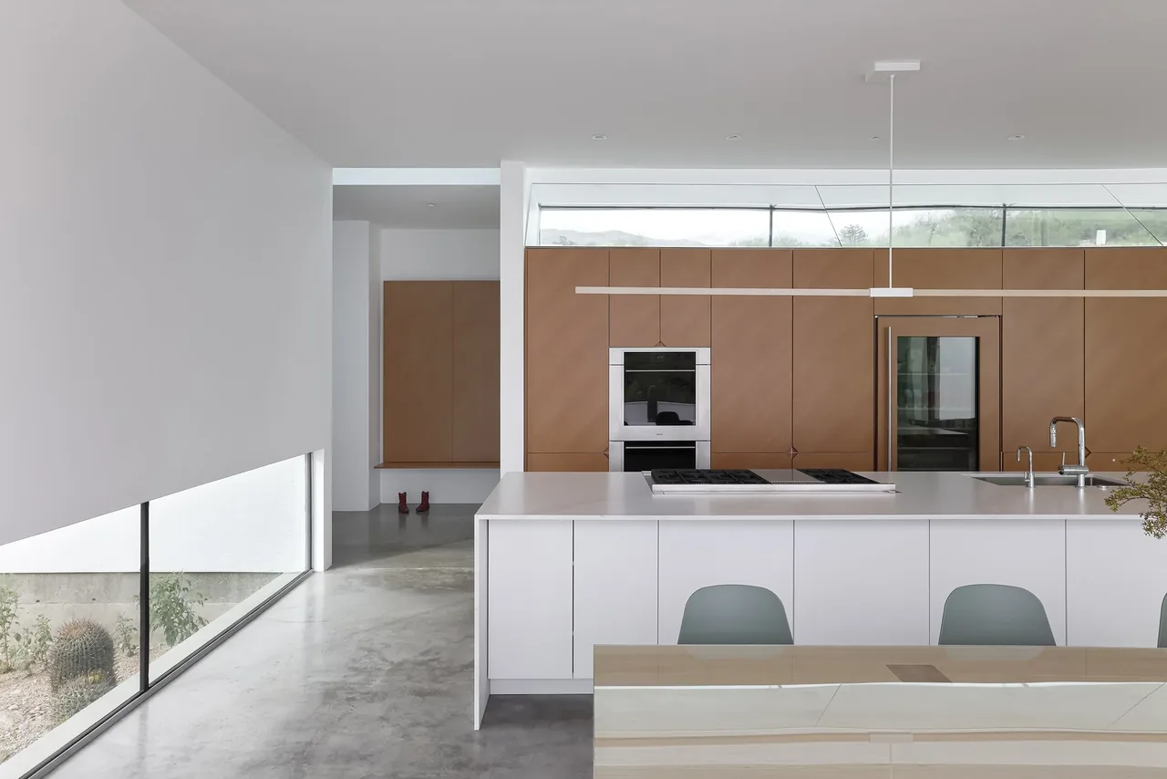 Kitchen featuring a white island with cooktop and brown cabinetry under a clerestory window.