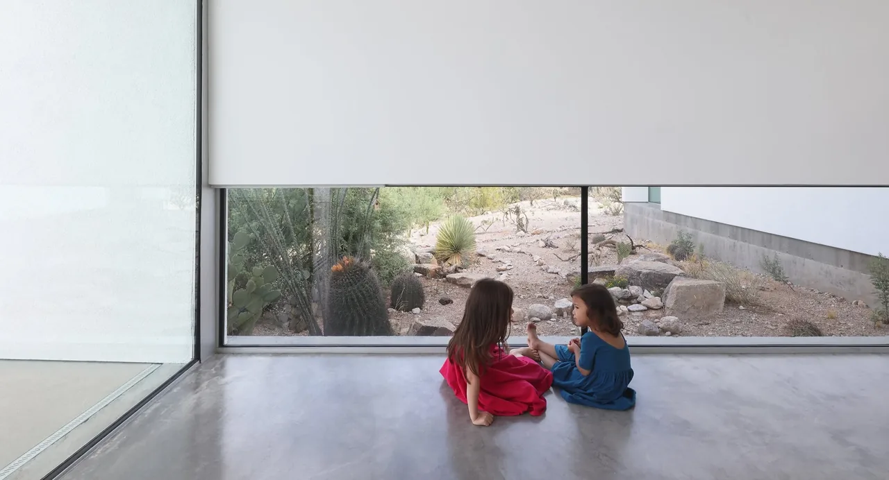 Interior view showing polished concrete flooring and floor-to-ceiling window with desert landscaping outside.