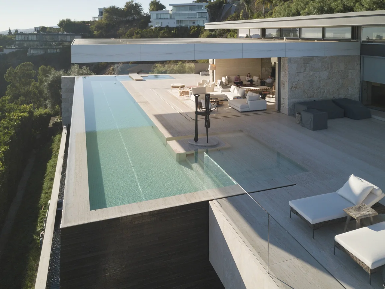 Terrace with glass-railed infinity pool and outdoor lounge area at Hollywood Residence by Horst Architects.