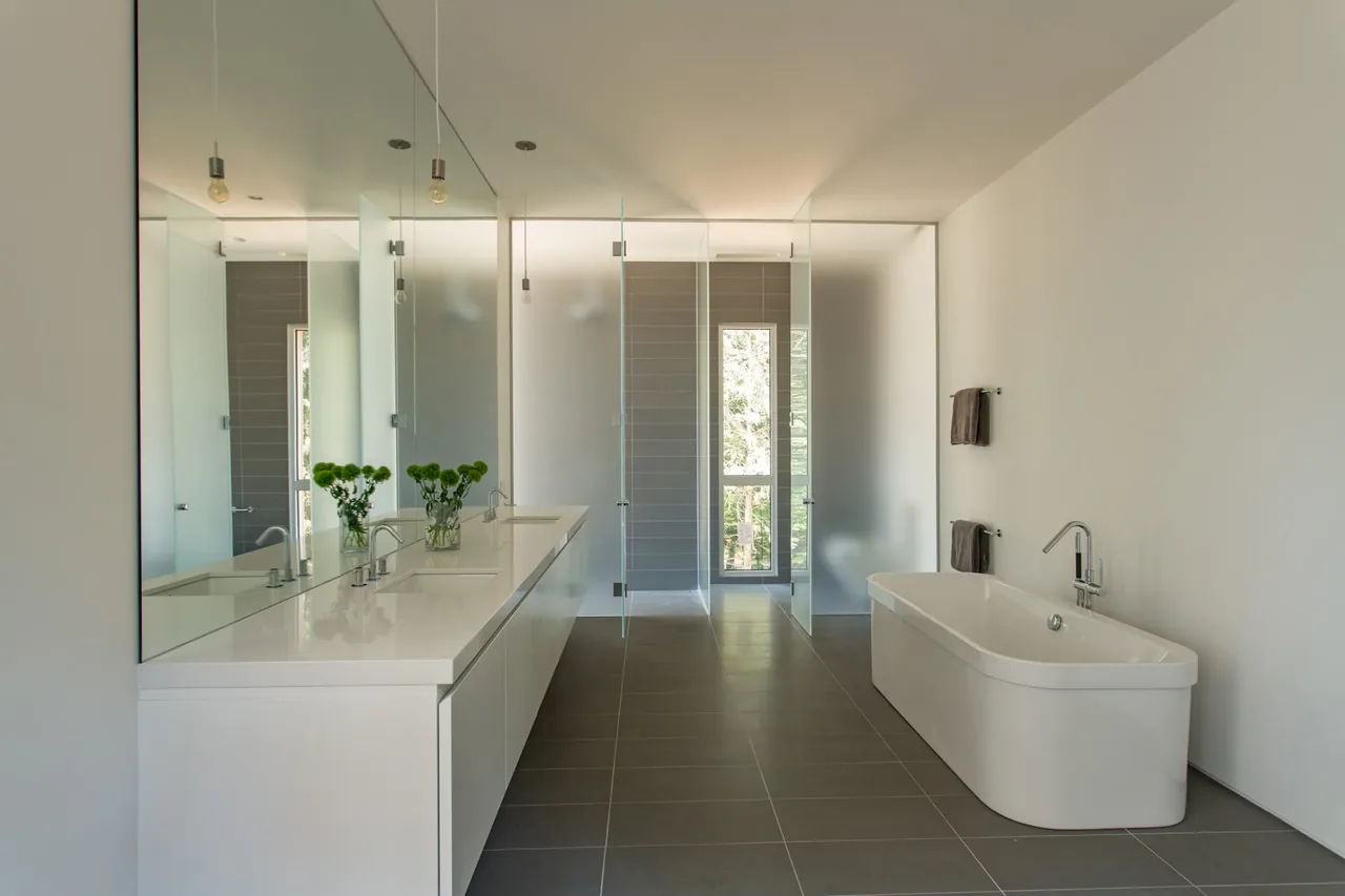 House No.207 bathroom features a double vanity, freestanding tub, and frosted glass partitions by jacob lilley architects.