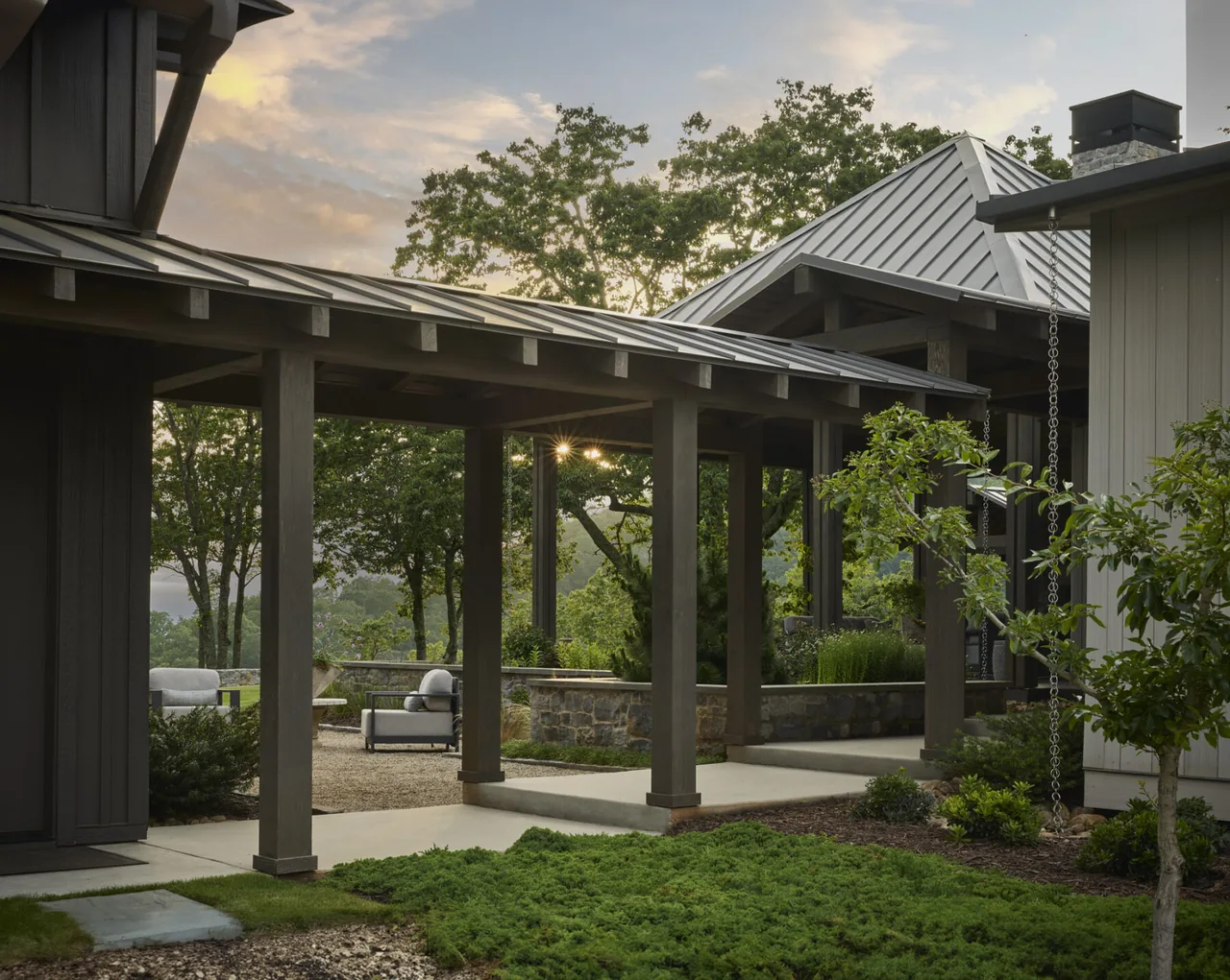 The mountain lake renovation features a covered walkway with exposed beams and metal shed roofs connecting building sections.