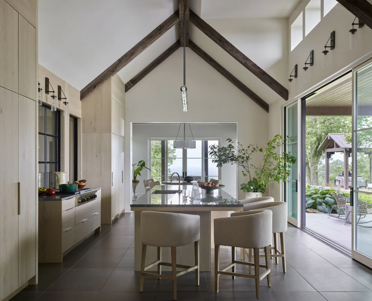 Kitchen with vaulted ceiling and exposed beams extends to outdoor patio through sliding glass doors.
