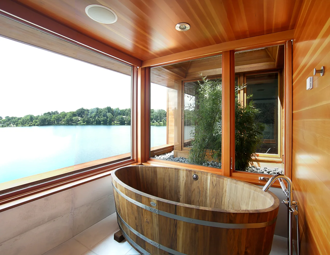 Bathroom with a wooden soaking tub and large windows providing a lake view in the Connecticut Lake House.