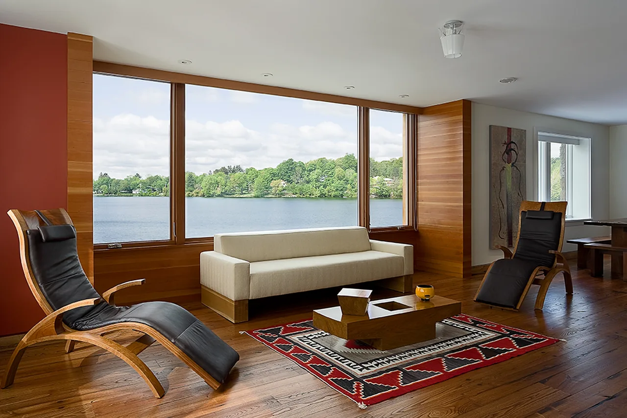 Living room of CONNECTICUT LAKE HOUSE with wood flooring and a large picture window facing the lake.
