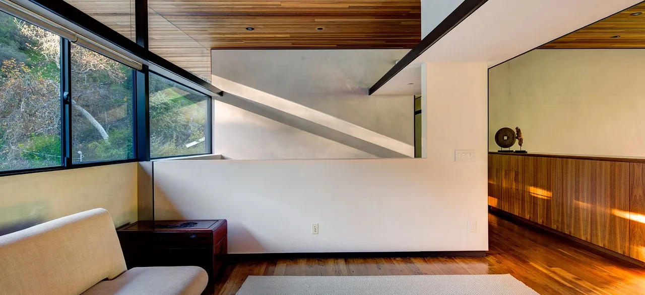 Living area features angled corner windows and a wood ceiling with slats.