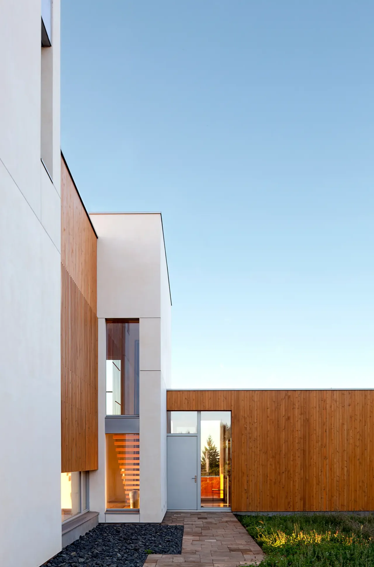 Karuna House by Holst Architecture P.C. features minimalist cubic volumes with white stucco and vertical wood siding on a hilltop.