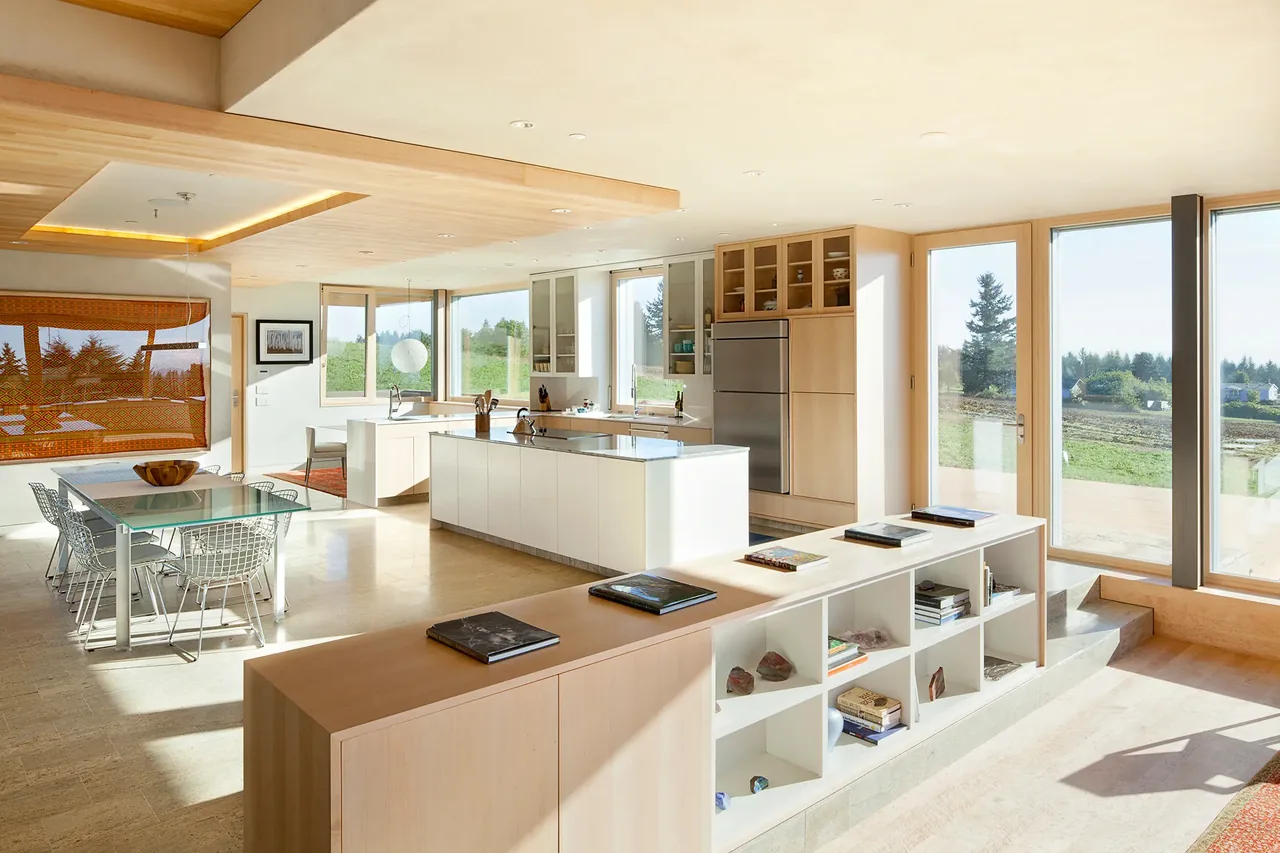 Daylight fills this open kitchen and dining space featuring glass doors leading outside and wood cabinetry.
