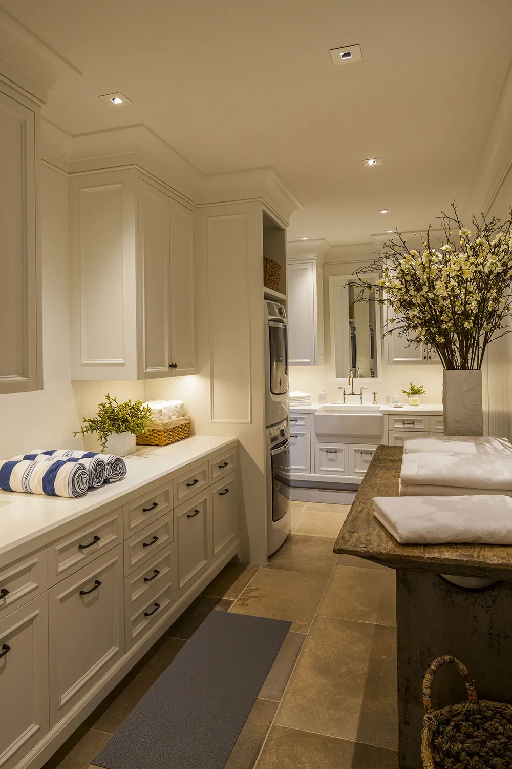 Laundry room featuring built-in stacked washer and dryer, farmhouse sink, and rustic wood folding table.
