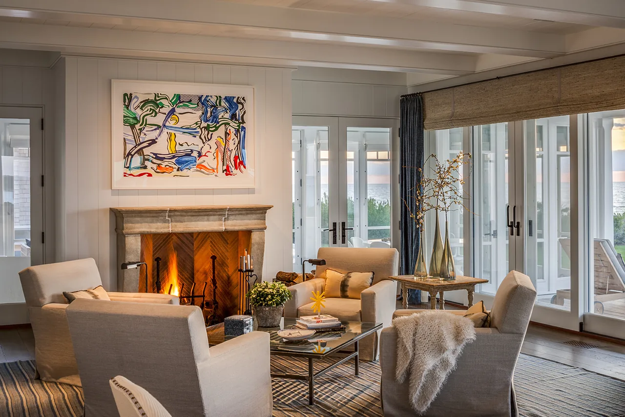 Living room featuring a stone fireplace and floor-to-ceiling windows with a view of the water.