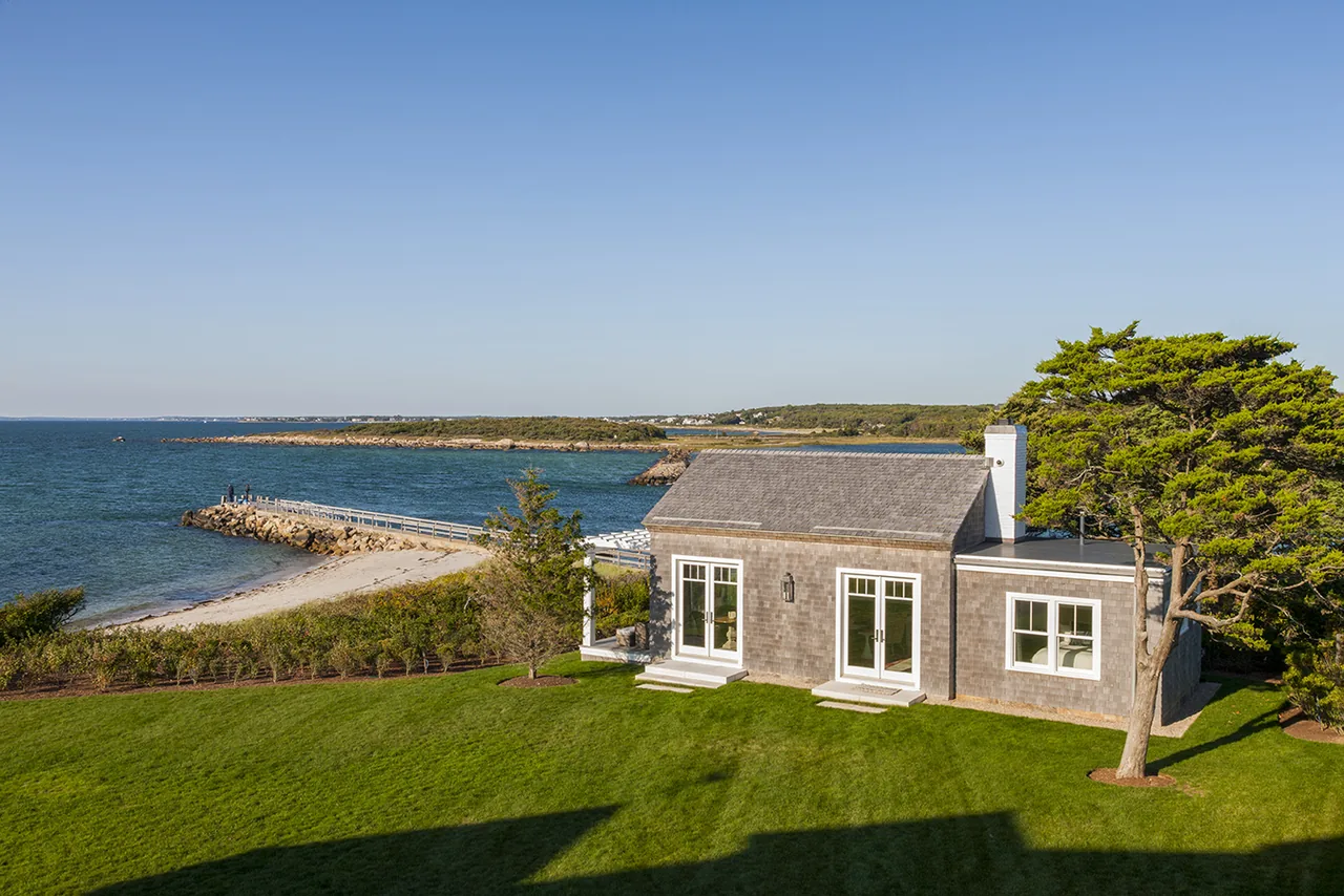 Shingle-sided coastal house with a pitched roof and symmetrical windows overlooking the ocean at West Bend Point.