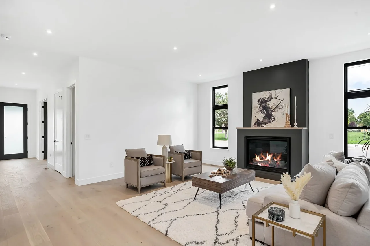 The living space features light wood floors, a black fireplace wall, and minimal decor with natural tones.