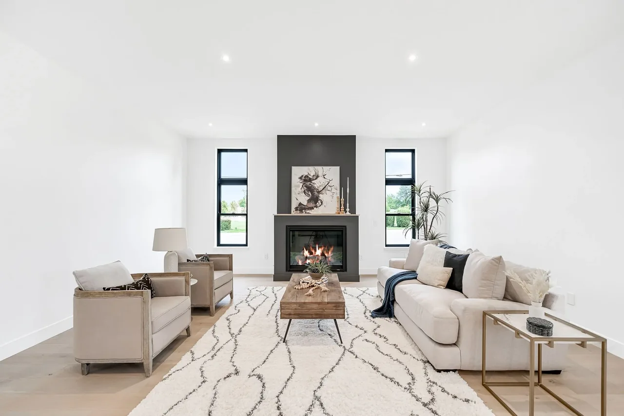 Living room with a central fireplace and tall black-framed windows on each side.