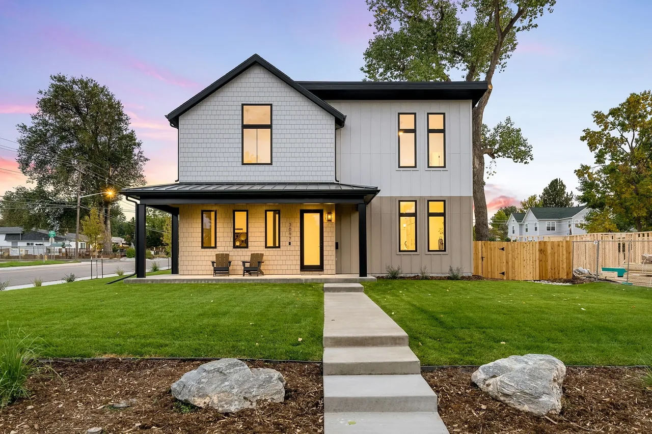 Two-story house with white shingle and board siding, black window frames, and a covered front porch by Dokken Built.
