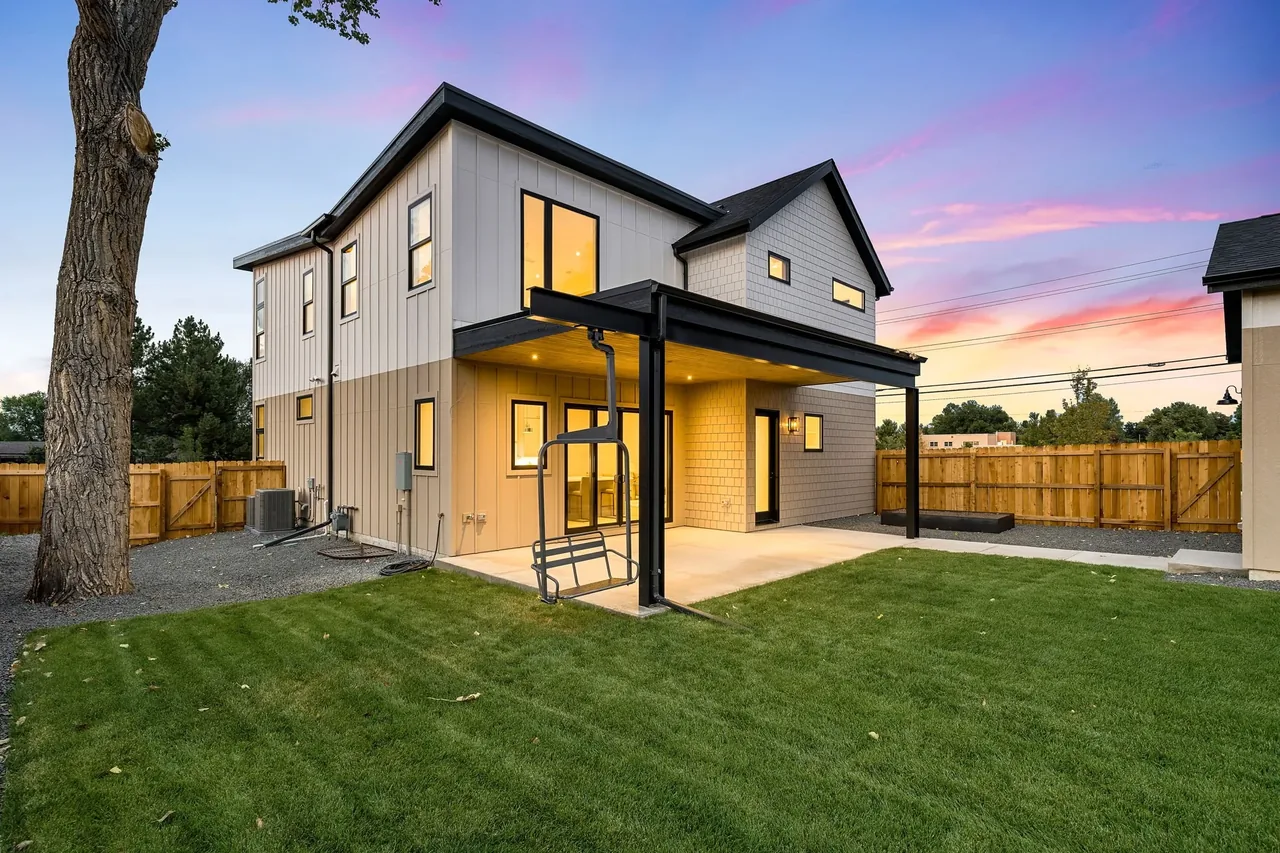 Modern two-story home with board siding and a covered patio featuring a hanging bench at 3097 S Dexter Way.