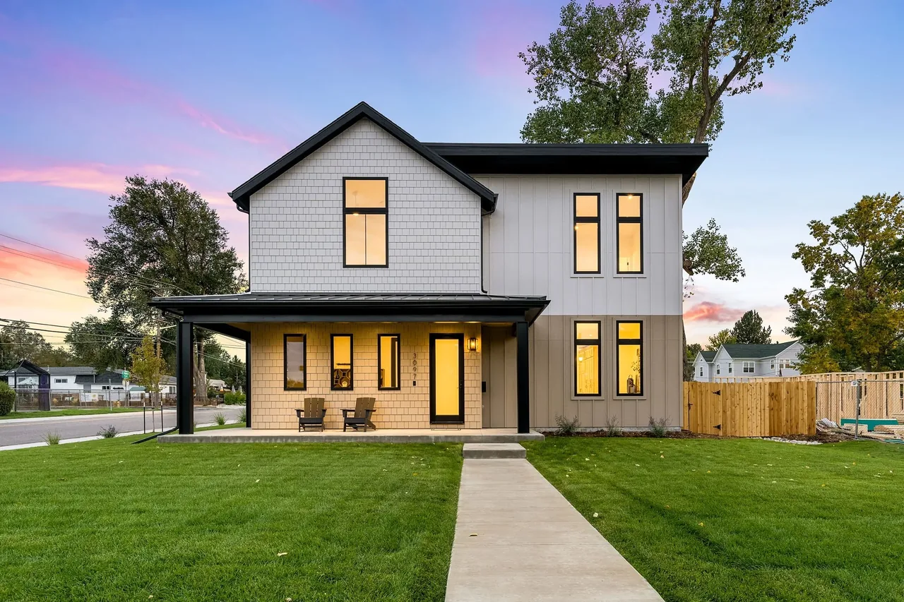 The house features a combination of shingle and vertical siding with black window frames and a covered front porch.