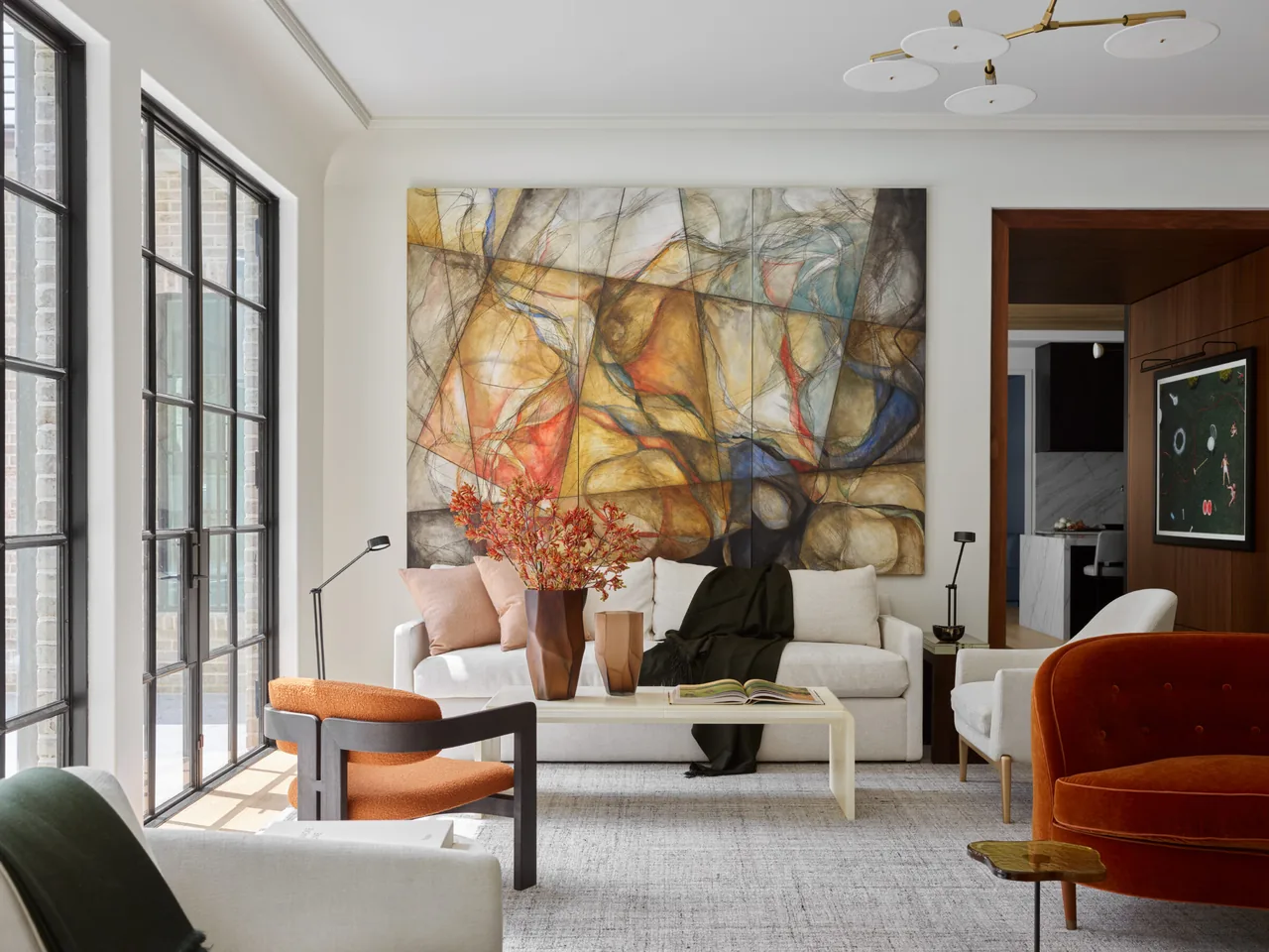 Modern English Manor living room by Harrison Design Associates features an abstract painting and large black window frames.