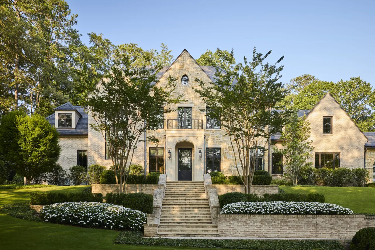 Large stone and brick two-story manor house with a central staircase and a steep gable roof.