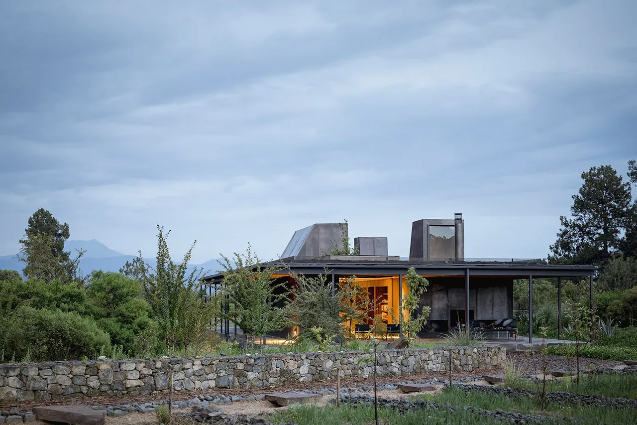 Casa Temascaltepec by Hutchison & Maul Architecture features a flat green roof and rusted metal accents in a forested landscape.